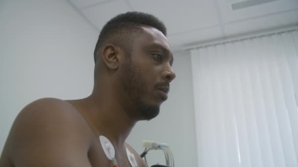 Afroamerikansk Mand Med Holter Sensorer Pedaler Orbitrek Kardiologi Værelse Funktionel – Stock-video