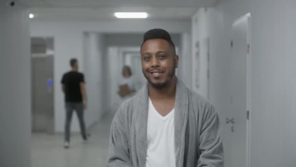 행복한 아프리카계 미국인 남자는 복도에 미소와 카메라를 클리닉에서 재활하는 환자를 — 비디오