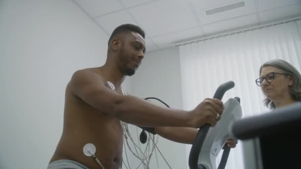 Homem Afro Americano Com Sensores Holter Pedais Orbitrek Sala Cardiologia — Vídeo de Stock