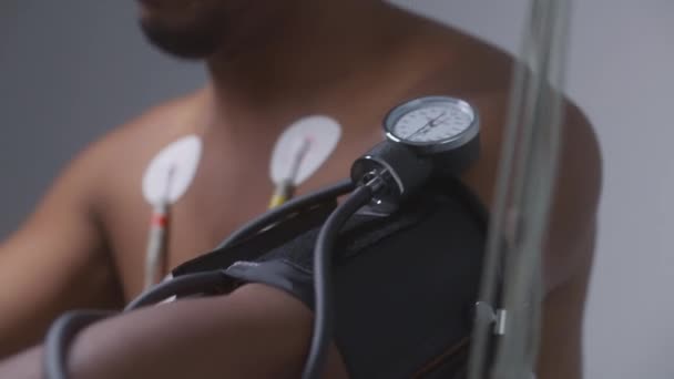 Afroamerykanin Pacjent Tonometrem Czujnikami Pedałuje Orbitrek Sali Kardiologicznej Podczas Pomiaru — Wideo stockowe