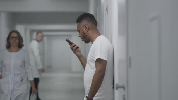 Sjukhuskorridoren Afroamerikansk Man Spelar Röstmeddelanden Och Surfar Internet Telefon Återställning — Stockvideo