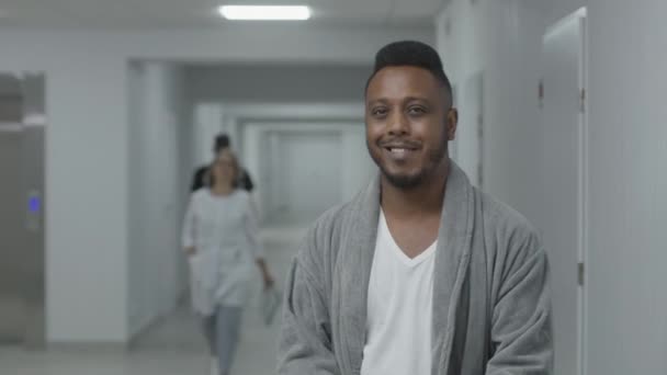 행복한 아프리카계 미국인 남자는 복도에 미소와 카메라를 진료소에서 환자를 복구합니다 — 비디오