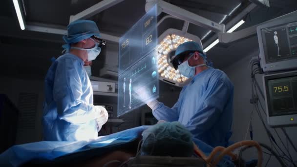 医師は Arヘッドセットを着用した病院手術室で手術を行います 重要な兆候と患者の状態を示す仮想Aiホログラフィックディスプレイの3Dグラフィック Vfxアニメーション 現代医学コンセプト — ストック動画