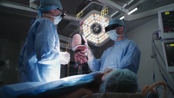 外科医は Arヘッドセットを着用した病院手術室で患者を操作します 重要な兆候と人間の臓器を示す仮想Aiホログラフィックディスプレイの3Dレンダリング Vfxアニメーション 現代医学の概念 — ストック動画