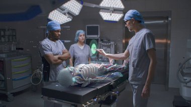 Çok ırklı cerrahlar hastane ameliyathanesinde çalışır. Sanal hologramın 3 boyutlu grafikleri insan iskeleti, beyin ve yaşam belirtilerini gösteriyor. VFX animasyonu. Tıptaki yapay zeka teknolojileri. Gelecekteki sağlık hizmetleri.
