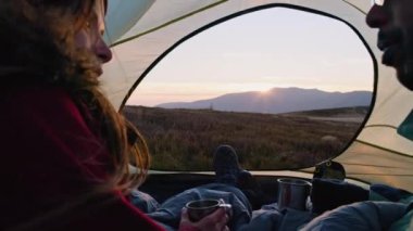 Tepedeki çadırda dinlenen genç bir aile. Afrikalı Amerikalı adam beyaz karısıyla konuşuyor. Birkaç turist çay içip gün batımını seyrediyor. Yürüyüşçüler tatilde dağlarda manzaranın keyfini çıkarırlar.
