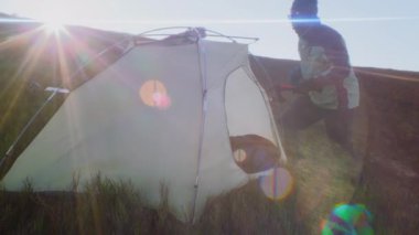 Elinde balta olan Afrikalı Amerikalı bir adam dağın tepesine çadır kuruyor. Turist ısınır ve tepede bir fincan sıcak çay içer. Sırt çantalı arkadaşlar yürüyüş sırasında dinlenmek için durdular. Rüzgarlı ve soğuk hava.