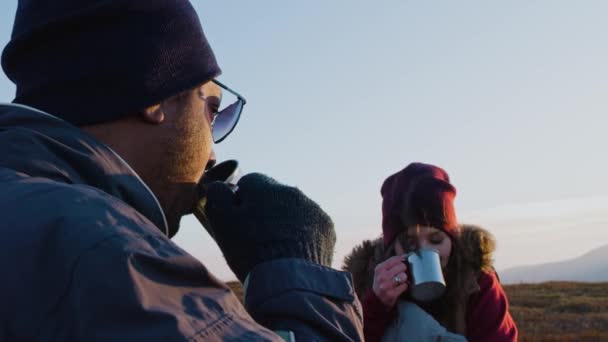 接近非洲裔美国男人喝茶和与白人女人交谈 一对年轻的徒步旅行者在山顶上休息 欣赏风景 多民族旅游者去山上度假 — 图库视频影像