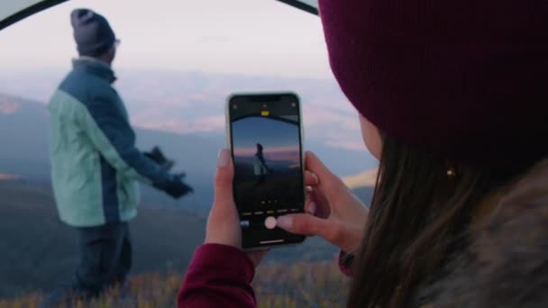 女人用电话在美丽的山景上给游客拍照 手持斧头的非洲裔美国徒步旅行者站在山上 背包客在探险度假期间停下来休息 靠近点 — 图库视频影像