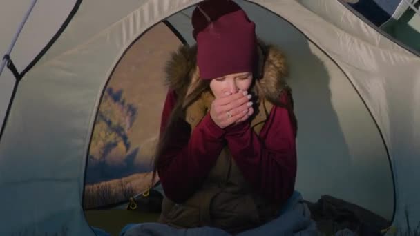 若い女性はテントに座り 凍った手を温め それらをこすり 手のひらに吹きかけます アフリカ系アメリカ人は山の上にテントを置く 多様な観光客カップルはハイキング中に休憩するために停止しました — ストック動画