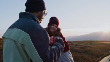 Genç aile tepenin üstünde duruyor ve kadeh kaldırıyor. Beyaz kadın Afrikalı Amerikalı kocasıyla konuşur ve gün batımını seyreder. Çok ırklı iki turist, dağlardaki tatillerinin tadını çıkarıyor..