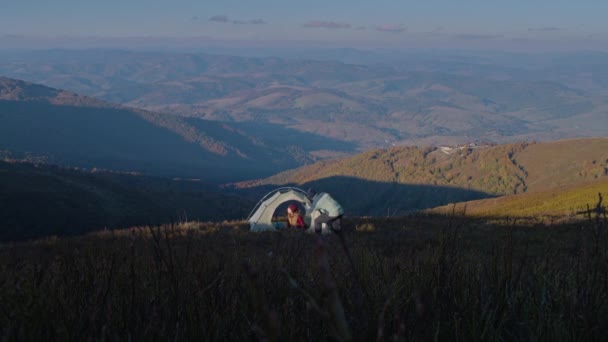 非裔美国男人在山顶上搭帐篷 女人帮助他 多民族背包客朋友们在美丽的山岗上探险 多姿多彩的游客夫妇在远足途中停下来休息 — 图库视频影像