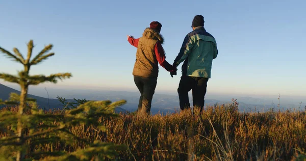Tourist couple walk beautiful mountain valley. Female traveler with African American man come to admire awesome landscape. Greenery sways by strong wind. Awesome view of nature scenery. Slow motion.