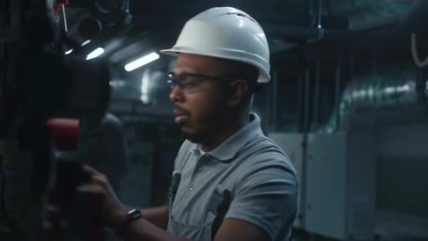 专业的重工业工人检查并建立管道系统 非裔美国工程师在工作场所手指受伤 在现代化工厂 工厂或能源设施工作的工业专家 — 图库视频影像