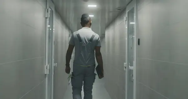身穿制服的非裔美国工程师手持平板电脑 走在现代制造厂的走廊上 工业设施办公大楼走廊内的重工业工人 慢动作 — 图库照片