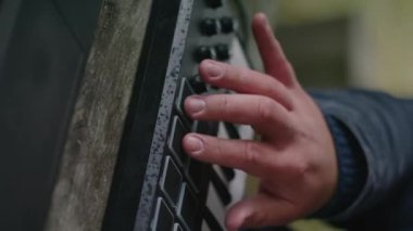Kafkasyalı bir adamın tuşlara basıp açık havada MIDI kontrolörüyle oynamasına yakın durun. Profesyonel erkek müzisyen dijital elektrikli piyano kullanır, müzik yaratır ve kaydeder. Dikey video.