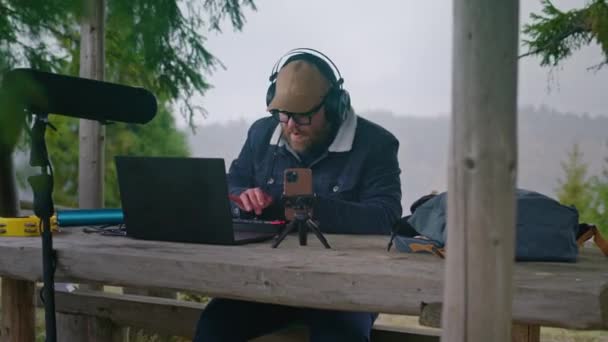 Καυκάσιος Μουσικός Ακουστικά Κάθεται Στο Τραπέζι Στο Κιόσκι Φορητό Υπολογιστή — Αρχείο Βίντεο