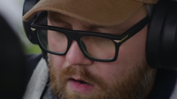 男性音乐家戴着眼镜和耳机 弹奏Midi键盘 谱写音乐 有节奏地坐在室外活动 白种人度假期间在山上录制新歌 — 图库视频影像