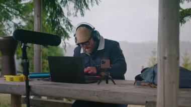 Kulaklıklı beyaz müzisyen ormanda çardakta oturarak şarkı bestelemek için MIDI klavye kullanır. Yetişkin bir adam dağlarda tatildeyken telefon ve dizüstü bilgisayarla müzik yaratır ve kaydeder..