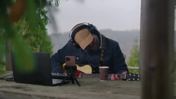 Kulaklıklı Beyaz Bir Adam Ormanda Tahta Bir Çardakta Gitar Çalar — Stok video