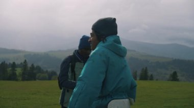 İki Afrikalı Amerikalı turist tepenin üstünde durup manzaraya hayran. Bir grup gezgin dağlarda uzun bir yürüyüşten sonra dinlenmek için durdu. Doğa keşfi ve turizm kavramı. Aktif boş zaman.