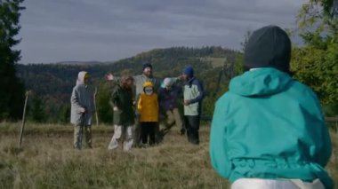 Genç yürüyüşçü, tepedeki çok ırklı arkadaşlarının ya da ailesinin güzel manzaralı fotoğraflarını çekiyor. Dağlarda yürüyüş yaparken çeşitli turistler veya gezginler. Aktif boş zaman.