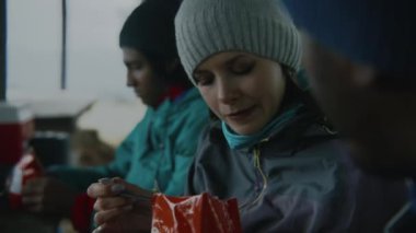 Çok ırklı iki gezgin, keşif sırasında donmuş, kurutulmuş, yürüyüş yapan yiyecekler yiyor. Bir grup turist ya da yürüyüşçü uzun bir yürüyüşten ya da dağlarda yürüyüşten sonra ahşap taraçada dinleniyor. Turizm konsepti.