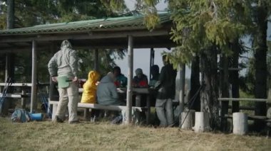 Çeşitli yürüyüş arkadaşları konuşur ve akşam yemeği için kese içinde yürüyüş yemeği hazırlarlar. Bir grup turist ormanda yürüdükten sonra taraçada dinleniyor. Gezi sırasında yürüyüşçüler ya da tatilde dağlara yolculuk yapanlar.