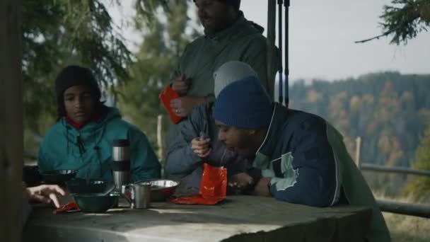 白人成年妇女与非洲裔美国丈夫共享袋装远足食物 一群多样化的游客在长途跋涉之后在加泽博休息 徒步旅行或在山上远足 — 图库视频影像