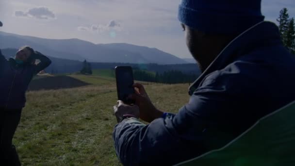 아프리카계 미국인 남자는 전화를 풍경에 꼭대기에 코카서스 아내의 사진을 찍습니다 — 비디오