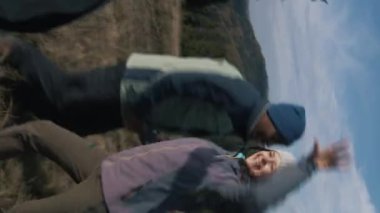 Telefon kamerasından POV. Kafkasyalı bir adam, blogcu tepede çok ırklı çocuklarla video kaydediyor ve kamerayla konuşuyor. Dağlarda yürüyüş yaparken çeşitli gezginlerden oluşan bir grup. Dikey video.