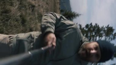 Akıllı telefon kamerasından POV. Selfie çubuğu olan yetişkin bir adam, kızı ve karısı tepenin üstündeyken video kaydediyor. Gezide mutlu turist aileleri ya da dağlarda gezintiler. Dikey görünüm.