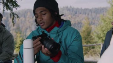 Çeşitli yürüyüş arkadaşları ormanda uzun bir yolculuktan sonra ahşap çardakta dinlenirler. Afrikalı Amerikalı gençler gülümser, konuşur ve kameralardan diğer turistlere fotoğraflar gösterir. Doğa keşfi ve turizm kavramı.