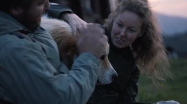 Tepede oturan, yerel köpekle oynaşan ve oynaşan Kafkas yürüyüşçülerine yakın bir yere. Gezginlerin ailesi yürüyüş sırasında dinleniyor ya da sonbaharda dağlarda yürüyüş yapıyor. Açık hava meraklıları.