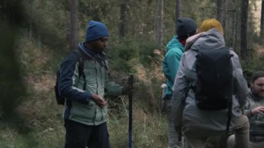 Bir grup çok ırklı yürüyüşçü dağlarda uzun yürüyüşler yaptıktan sonra dinlenmek için durdular. Gezginler orman kampında yemek yer ve konuşurlar. Turizm ve açık hava keşfi kavramı. Açık hava eğlencesi. Yavaş çekim.
