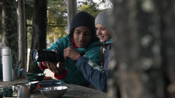 在森林里走了很长一段路之后 多样化的游客在木制的凉亭中休息 非洲裔美国青少年笑了 展示了他相机的照片 并与家人交谈 旅游业和积极休闲的概念 — 图库视频影像