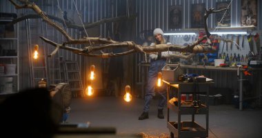 Dişi marangoz, ahşap işlemeyi tamamlıyor. Ampullü ağaç dalından alınan tasarım ürünlerine bakıyor. Modern atölyede marangoz kadın. El yapımı ve girişimcilik konsepti.