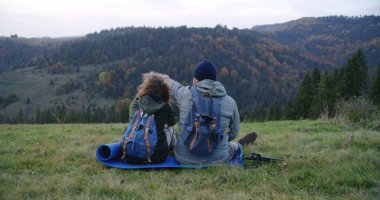 Sırt çantalı çeşitli yürüyüşçüler ve yürüyüş direkleriyle tepe boyunca manzaralı bir manzarayla yürüyorlar. Yürüyüş sırasında ya da dağlarda yürüyüş yaparken bir grup arkadaş ya da gezgin. Turizm ve aktif eğlence.