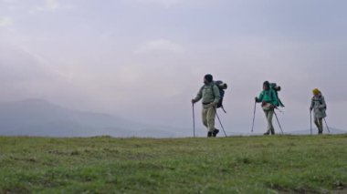 Sırt çantalı ve yürüyüş direkli bir grup yürüyüşçü güzel bir dağ tepesinde patika boyunca yürür. Çeşitli gezginler inanılmaz doğa manzarası keşfeder. Doğa keşfi ve turizm kavramı. Yavaş çekim.
