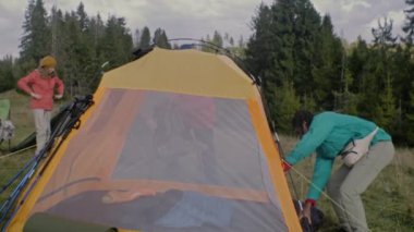 Çok ırklı bir grup açık hava meraklısı kamp kurdu. Afrikalı Amerikalı genç gezgin gitarı çadıra koydu. Turistler uzun bir yolculuktan sonra dinlenmek için durdular. Doğa keşfi kavramı. Yavaş çekim.
