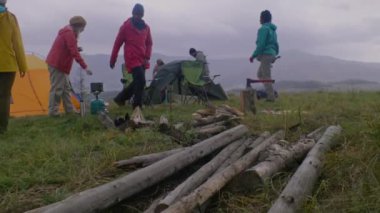 Çok ırklı turist grubu dağlarda kamp kuruyor. Yetişkin kadın, yürüyüş arkadaşları için gaz ocağında yemek pişiriyor. Afrikalı Amerikalı yürüyüşçü odun keser. Oğlu beyaz bir adam uydu interneti kurdu..