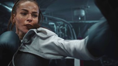 Spor salonunda antrenman yaparken yumruk tokuşturan atletik kadınlara yakın durun. Boks eldivenli kadın boksör dövüşmeden önce erkek antrenörle egzersiz yapıyor. Fiziksel aktivite ve egzersiz.