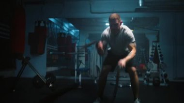 Karanlık boks salonunda LED ışıklandırmalı savaş halatlarıyla erkek atlet egzersizleri. Profesyonel boksör şampiyonluk maçından önce kardiyo ya da dayanıklılık egzersizi yapar. Fiziksel aktivite ve CrossFit eğitimi.