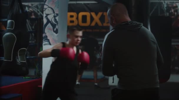 Сосредоточенный Молодой Боец Бьет Боксерскую Грушу Время Тренировки Темном Боксёрском — стоковое видео