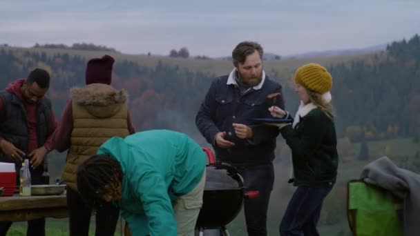 多民族夫妇带着孩子做饭 在山顶上吃烧烤 在户外休息 一群旅行者在周末旅行中一起玩得很开心 山区和森林背景 户外爱好者 — 图库视频影像