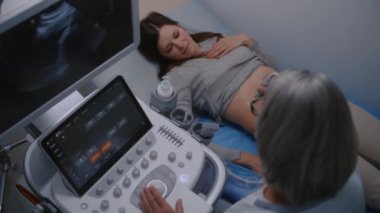 Kadın doktor, dijital monitörlü ultrason cihazı kullanarak midesinden kadın hastaya tıbbi muayene uygular. Beyaz kadın modern klinikte ya da hastanede ultrason kontrolünden geçiyor..
