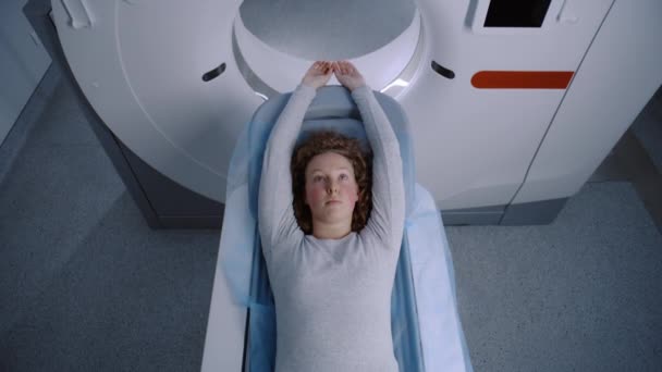 Pet Mriスキャンベッドに横たわる女性患者がマシン内部に移動するのを閉じます ハイテク機器は 最先端の技術を備えた医療施設で患者の体と脳をスキャンする — ストック動画