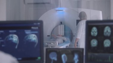 Profesyonel kadın doktor MRI veya CT 'yi veya PET taramasını hasta işlemleri ile kontrol eder. Kamera görüntüyü görüntülü beyin taramalarıyla değiştiriyor ve kontrol odasında sonuç veriyor. Sağlık Hizmetleri.