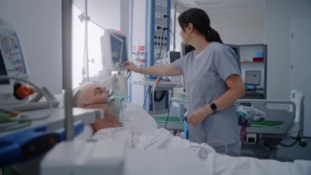 클리닉에 현대적인 장비를 응급실 마스크를 노인은 침대에 누워있다 친절한 간호사는 — 비디오
