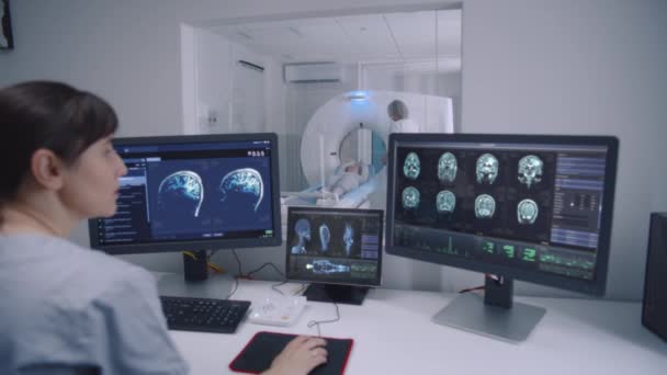 Radiolog Siedzi Pokoju Kontrolnym Obserwuje Monitory Wyświetlanymi Wynikami Skanów Mózgu — Wideo stockowe